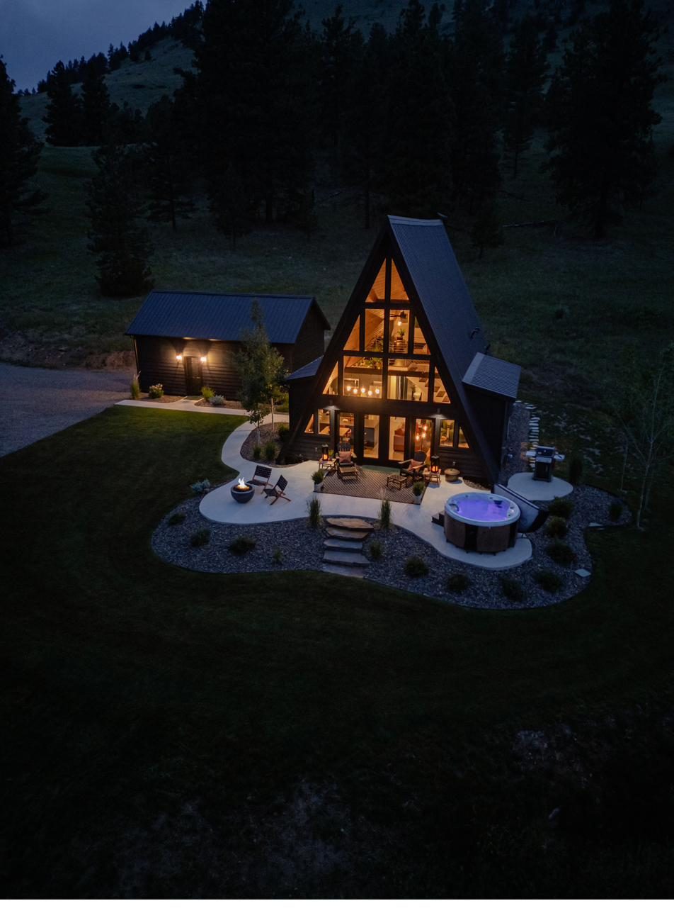 The Little Black A-Frame glowing at dusk in the Montana mountains