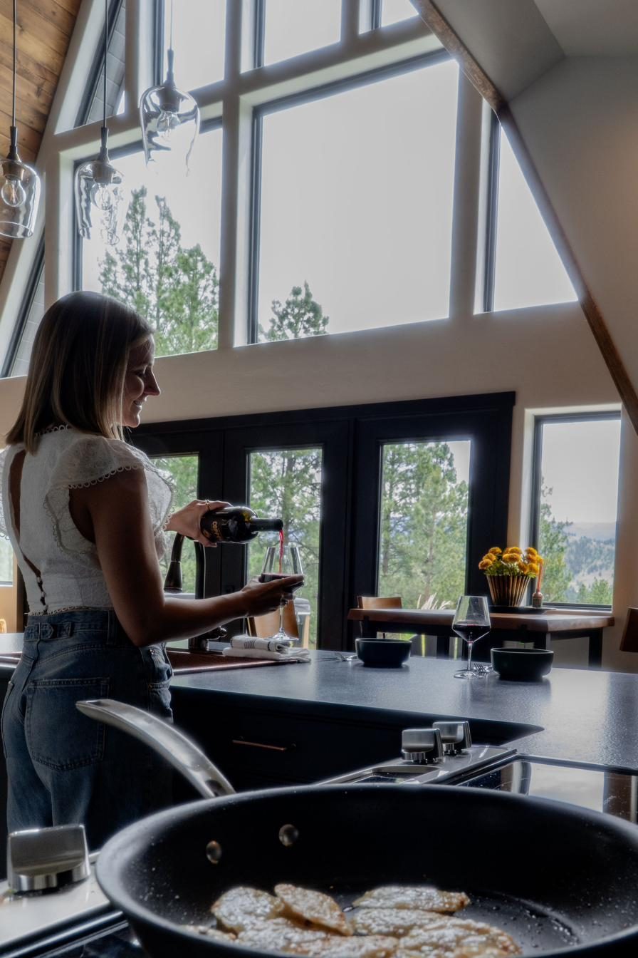 Pouring a glass of wine in the sunlit A-frame kitchen
